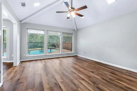 a view of wooden floor and a chandelier fan in a room