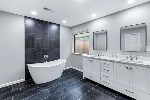 a bathroom with a double vanity sink a mirror and a bathtub