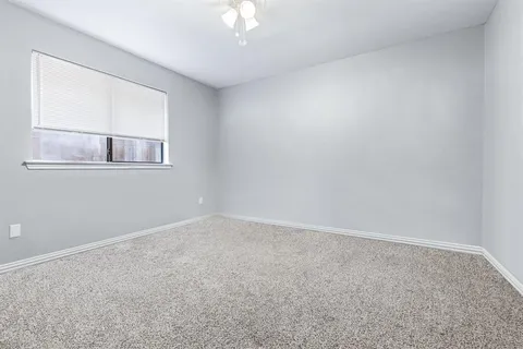 an empty room with a chandelier fan and windows