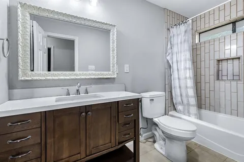 a bathroom with a toilet a sink a mirror a bathtub and shower