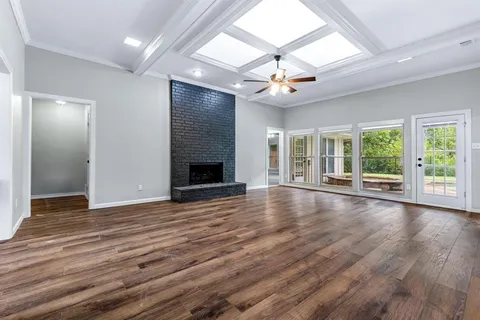 an empty room with wooden floor fireplace and windows