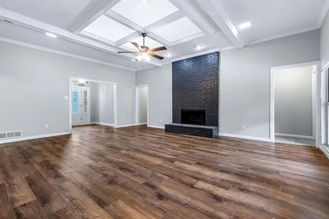 an empty room with wooden floor chandelier fan and windows