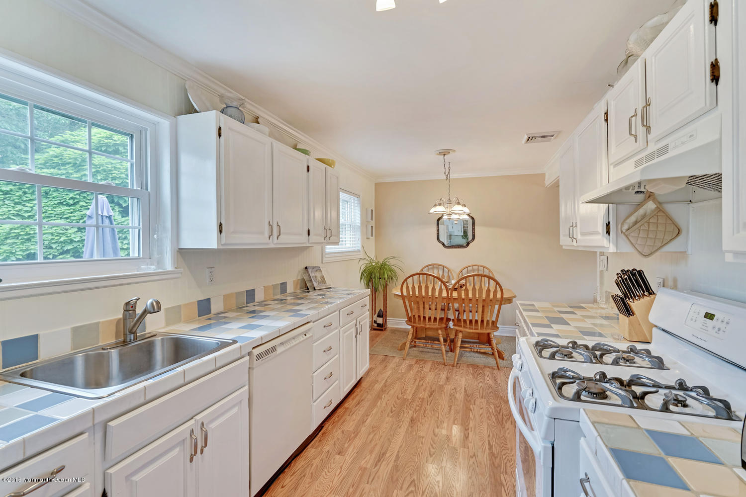 315 Stinson Road Brick, NJ 08723 - Photo 14 of 20 a kitchen with stainless steel appliances granite countertop a stove a sink dishwasher and white cabinets with wooden floor