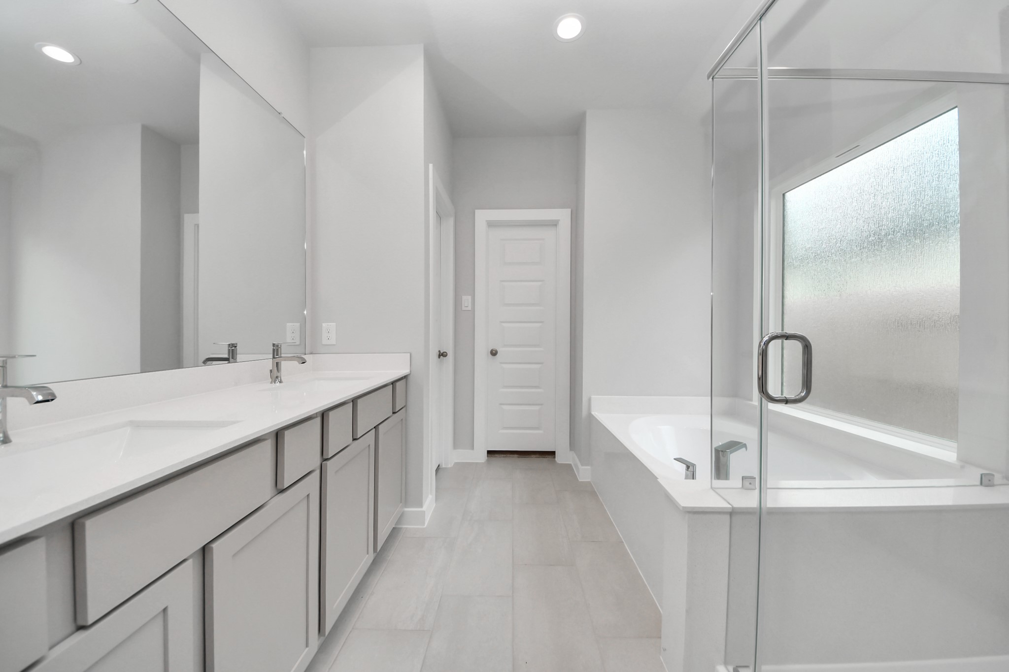 24518 Broad Park Spring, TX 77373 - Photo 23 of 29 Escape to a spa-like oasis in this primary bathroom. Enjoy a walk-in shower with tile surround, a separate garden tub with custom detailing, and an elegant vanity featuring light countertops, modern hardware, and beautiful vanity lights. Experience luxury and relaxation in every detail. Sample photo of completed home with similar floor plan. Actual colors and selections may vary.