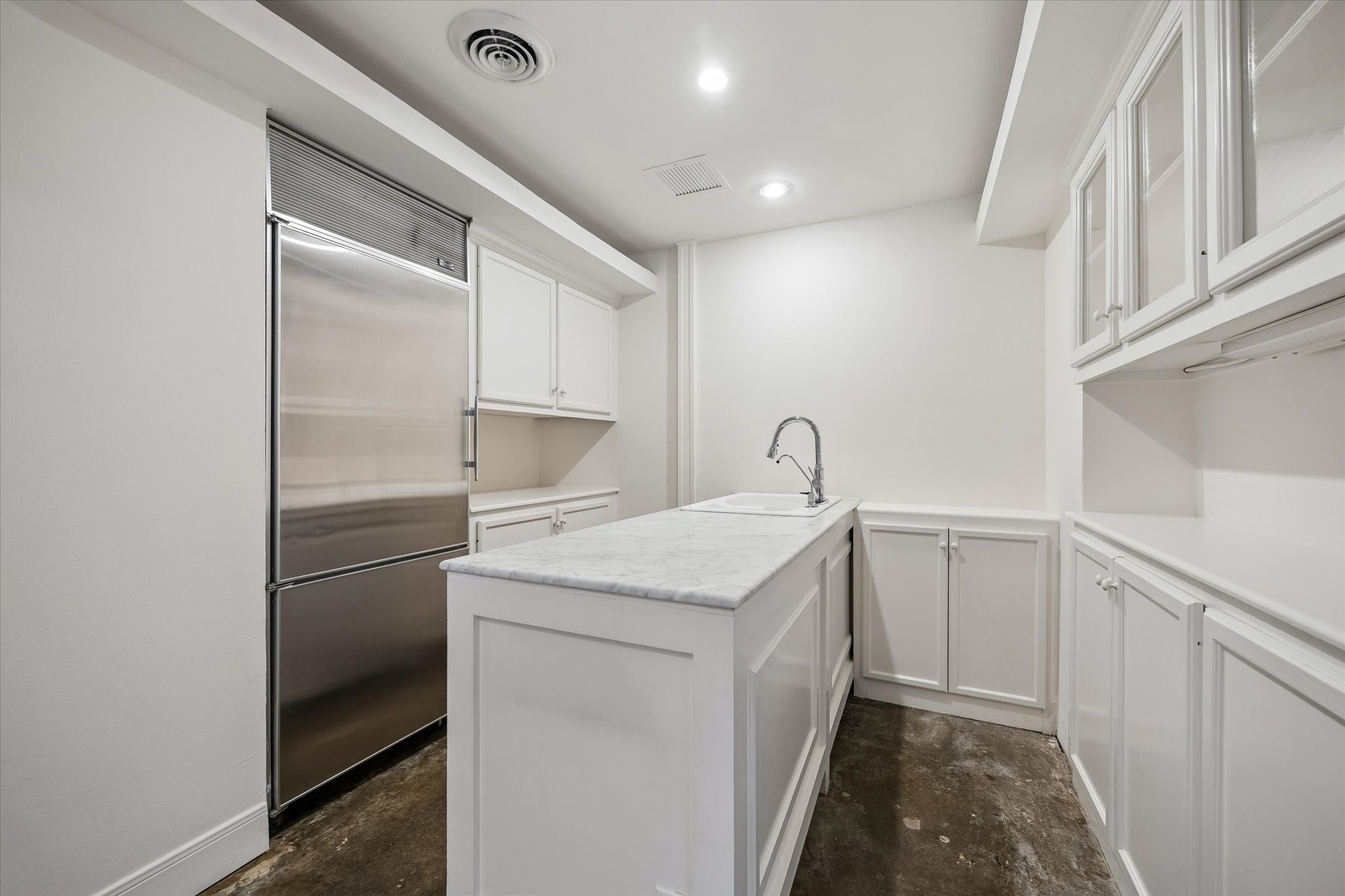 2701 Westheimer Road, Unit 2B Houston, TX 77098 - Photo 7 of 16 Kitchen offers island with sink, concrete flooring, and ample built-in cabinetry.