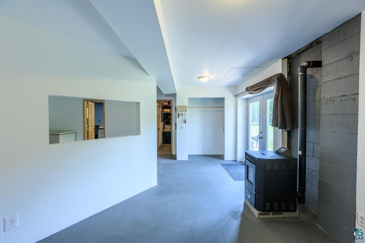 3201 Wilderness Road Makinen, MN 55763 - Photo 26 of 44 Open-concept area with concrete flooring, a pellet stove, double glass panel doors, and a partial wall opening
