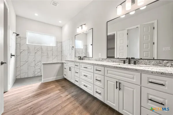 a bathroom with a double vanity sink a mirror and a bathtub