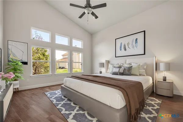 a bedroom with a bed painting on wall and a large window