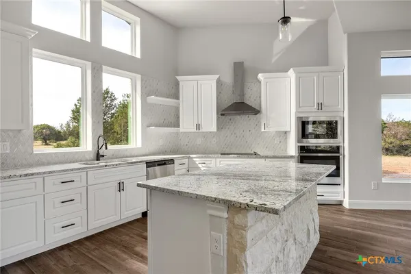 a kitchen with granite countertop a sink stove and cabinets