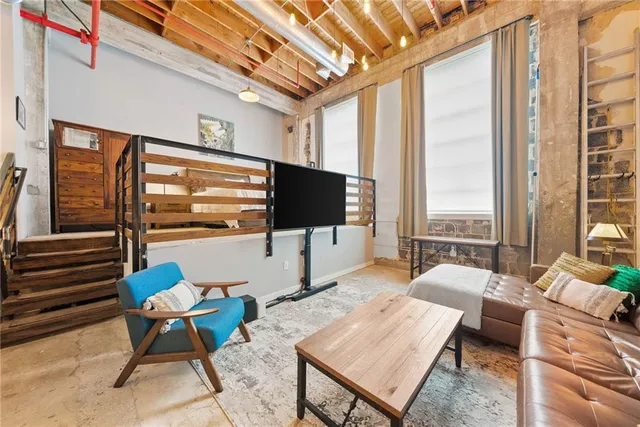 a living room with furniture a flat screen tv and floor to ceiling window