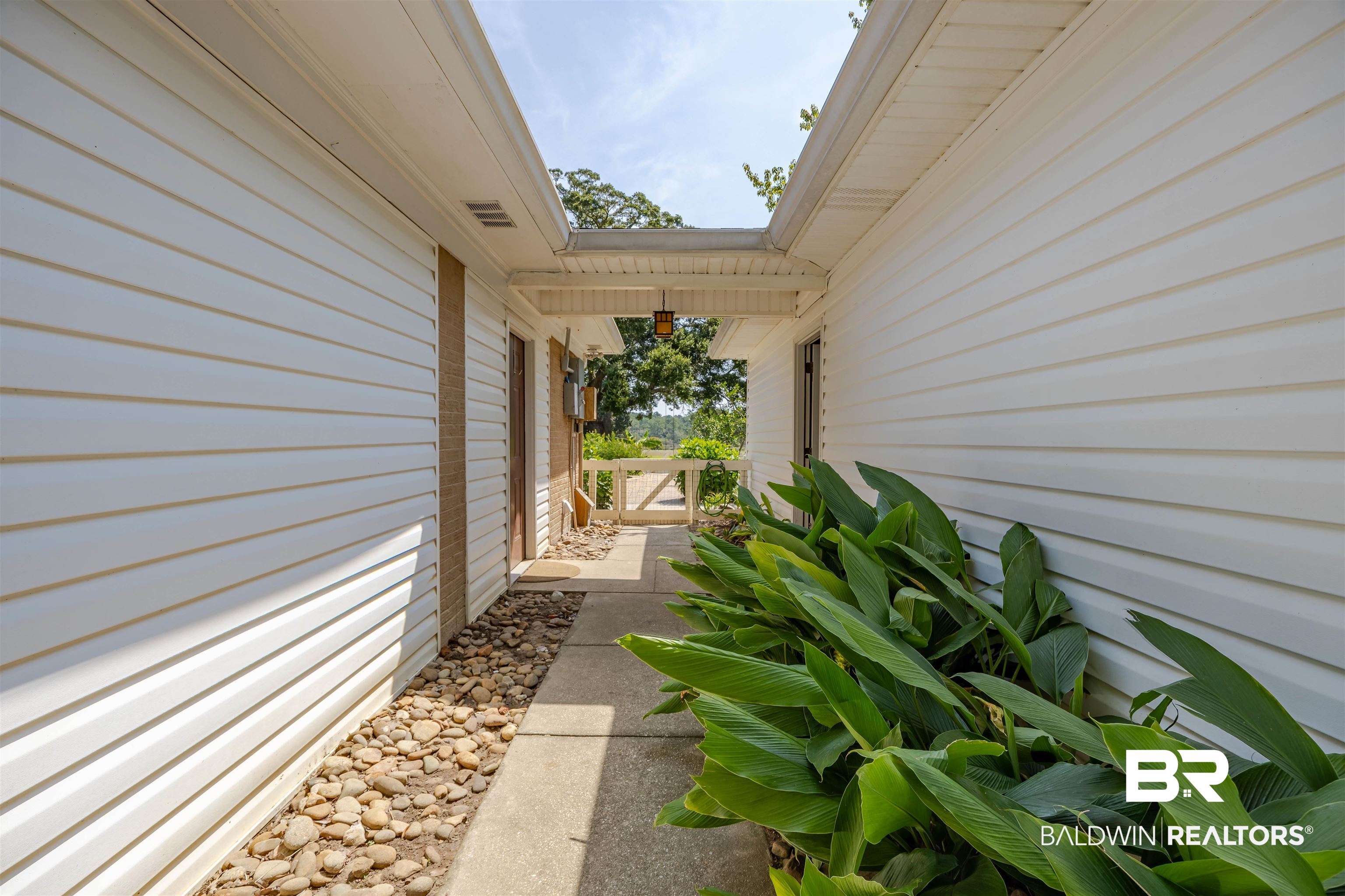 13677 Rebel Road Coden, AL 36523 - Photo 39 of 61 Covered breezeway featuring white siding, concrete walkway, and decorative landscaping