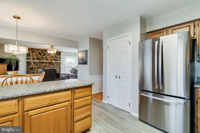 a kitchen with stainless steel appliances granite countertop a refrigerator a sink and white cabinets