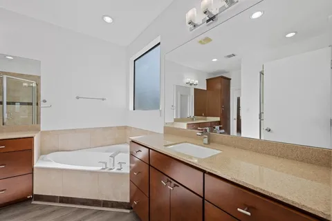 a bathroom with a bathtub a double vanity sink and mirror