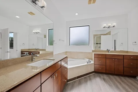 a bathroom with a tub double vanity sink and mirrors