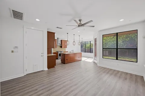 a view of a kitchen with a kitchen island wooden floor and stainless steel appliances