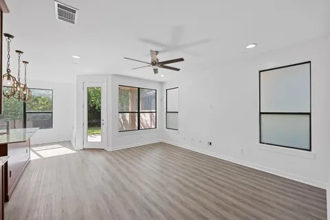 a view of an empty room with a window and wooden floor