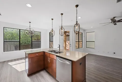 a kitchen with stainless steel appliances granite countertop a sink a stove and a wooden floor