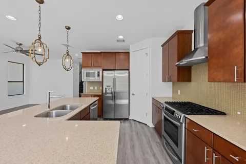 a kitchen with stainless steel appliances granite countertop a sink a stove and a wooden floor