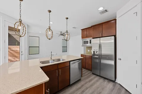 a kitchen with stainless steel appliances granite countertop a refrigerator a sink dishwasher a kitchen island with wooden floor and cabinets