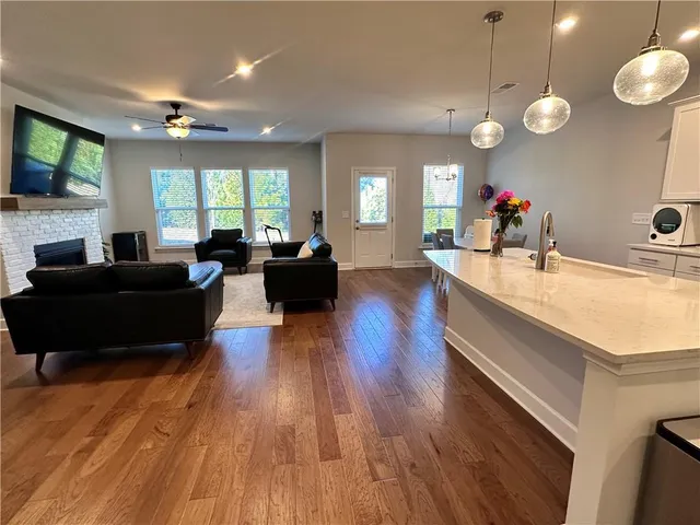 a living room with couches a flat tv screen and a dishwasher with kitchen view