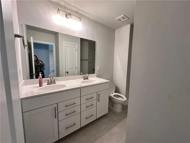 a bathroom with a double vanity sink a toilet and a mirror