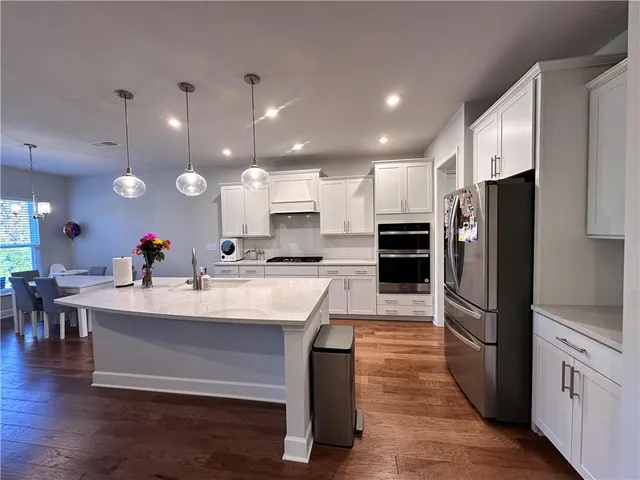 a large white kitchen with a refrigerator a stove a dining table and chairs