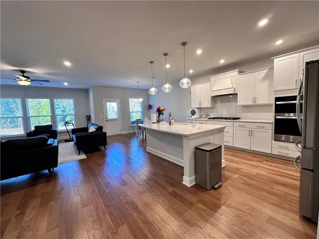 a living room with stainless steel appliances kitchen island granite countertop wooden floors and a view of living room