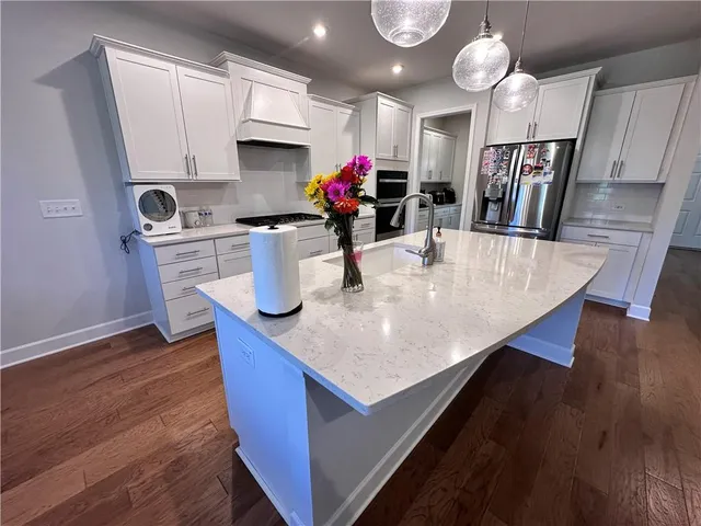a kitchen with stainless steel appliances granite countertop a sink dishwasher and a stove with wooden floor