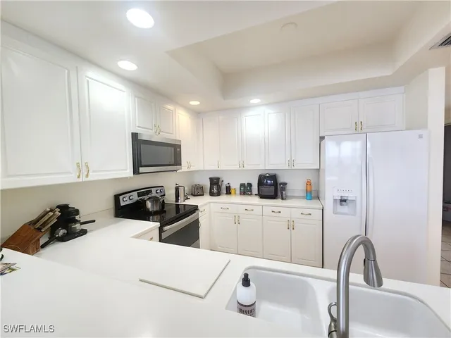 a kitchen with stainless steel appliances a refrigerator sink and white cabinets