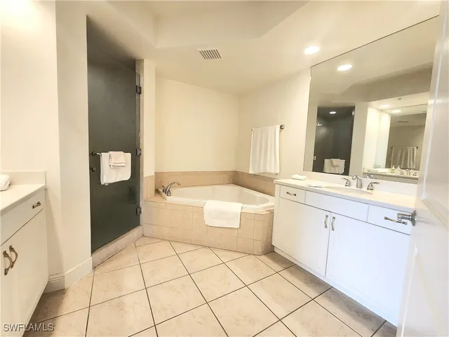 a bathroom with a granite countertop sink a mirror and a bathtub