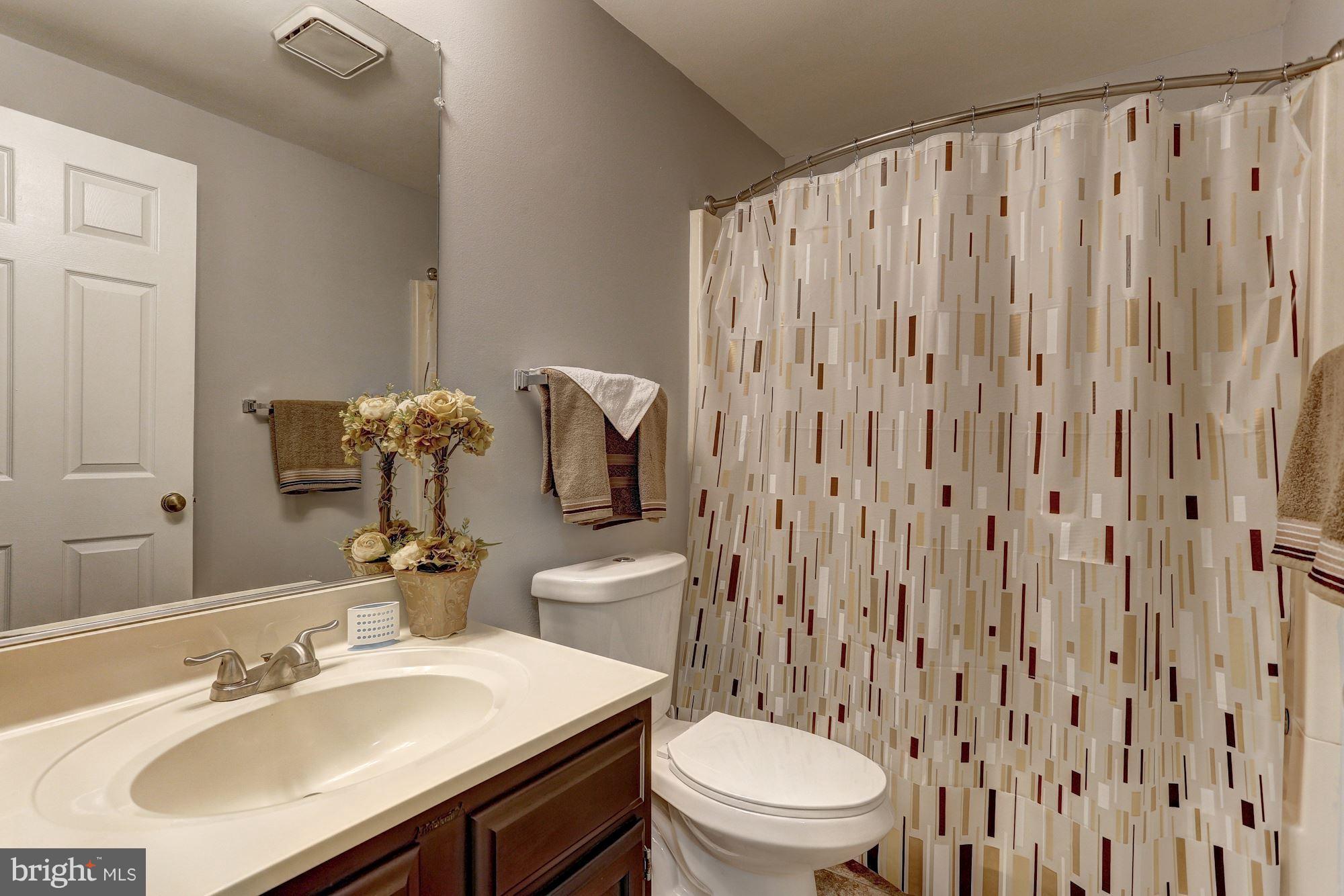 2302 Crossett Road Baltimore, MD 21237 - Photo 22 of 30 a bathroom with a sink a toilet and shower curtain