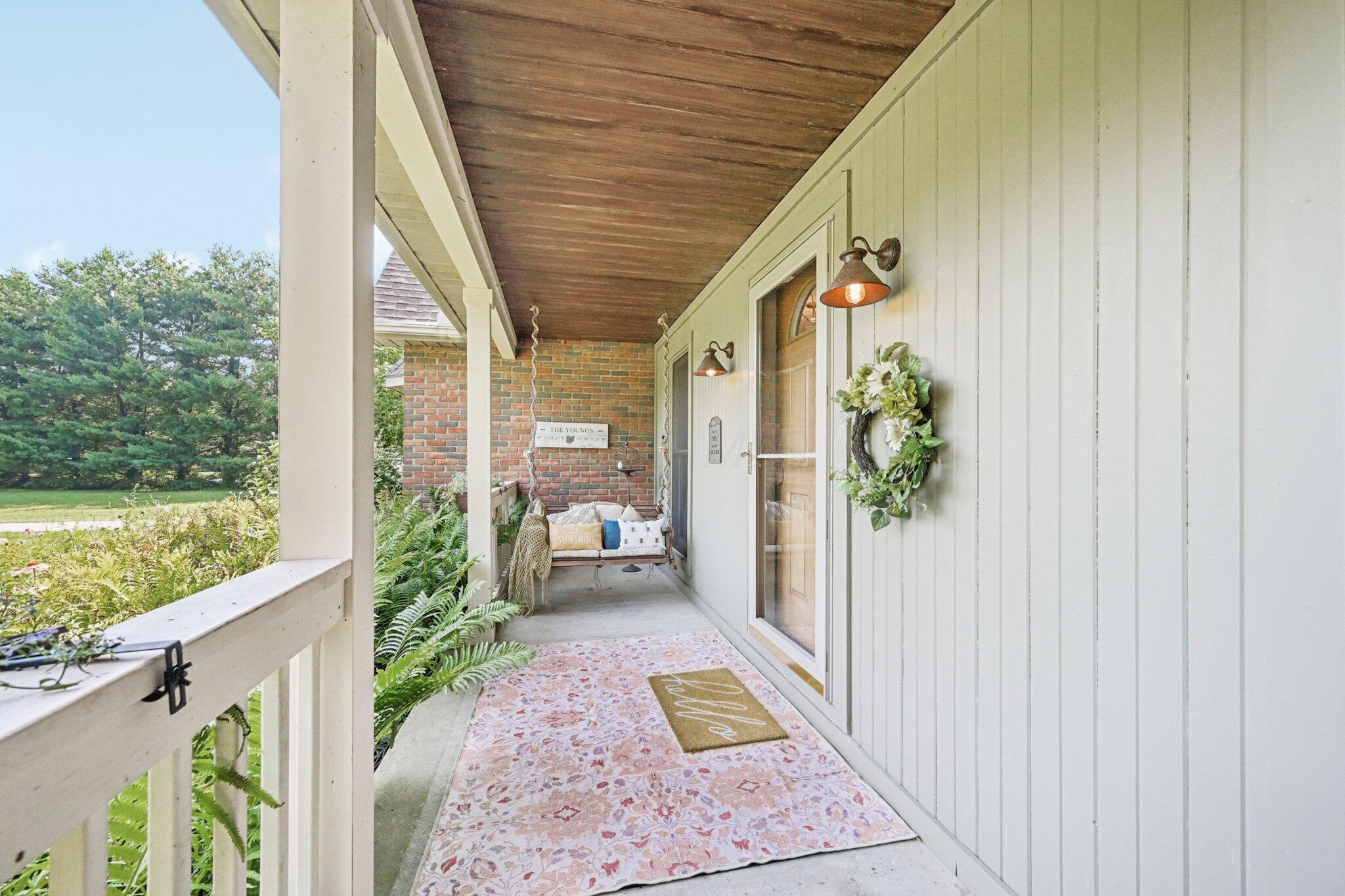 7700 Plumb Road Galena, OH 43021 - Photo 32 of 94 Another angle of the full-length porch with cozy seating area, perfect for sipping coffee or greeting guests.