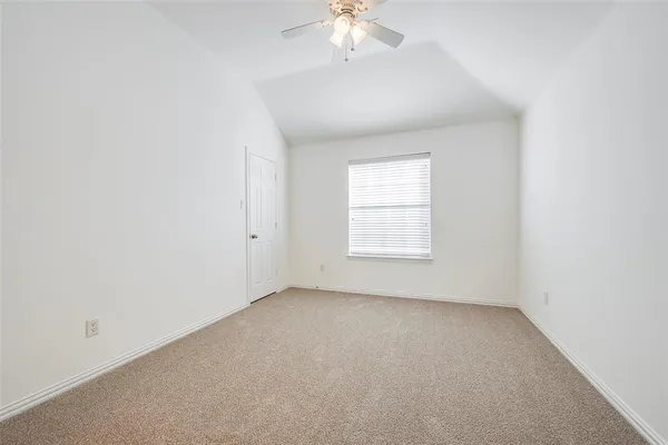 an empty room with a chandelier fan and windows