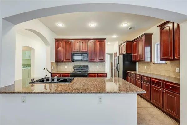 a kitchen with stainless steel appliances granite countertop a stove a sink a refrigerator and a microwave