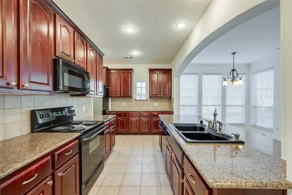 a kitchen with stainless steel appliances granite countertop a sink a stove and a wooden cabinets