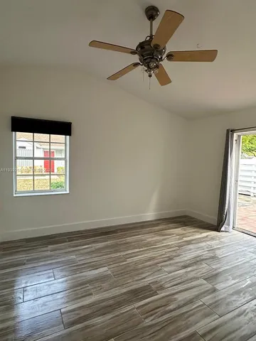 a view of empty room with wooden floor and fan