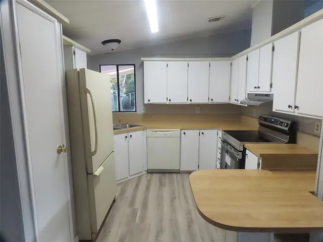 a kitchen with a refrigerator a stove and white cabinets