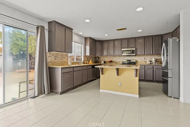 a kitchen with stainless steel appliances granite countertop a stove top oven a sink and a refrigerator