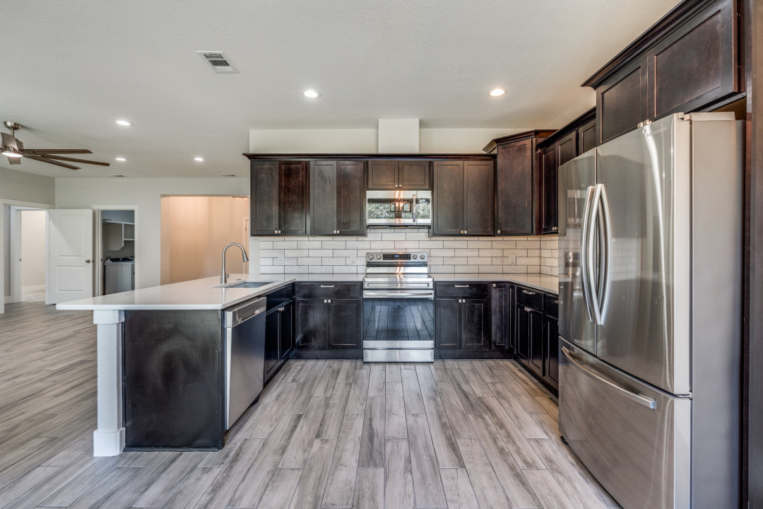 1848 Tanglewood Trail Spring Branch, TX 78070 - Photo 5 of 12 Modern kitchen with dark wood cabinetry and integrated stainless steel appliances.