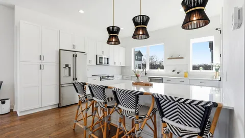 a kitchen with stainless steel appliances kitchen island granite countertop a table chairs in it and wooden floors