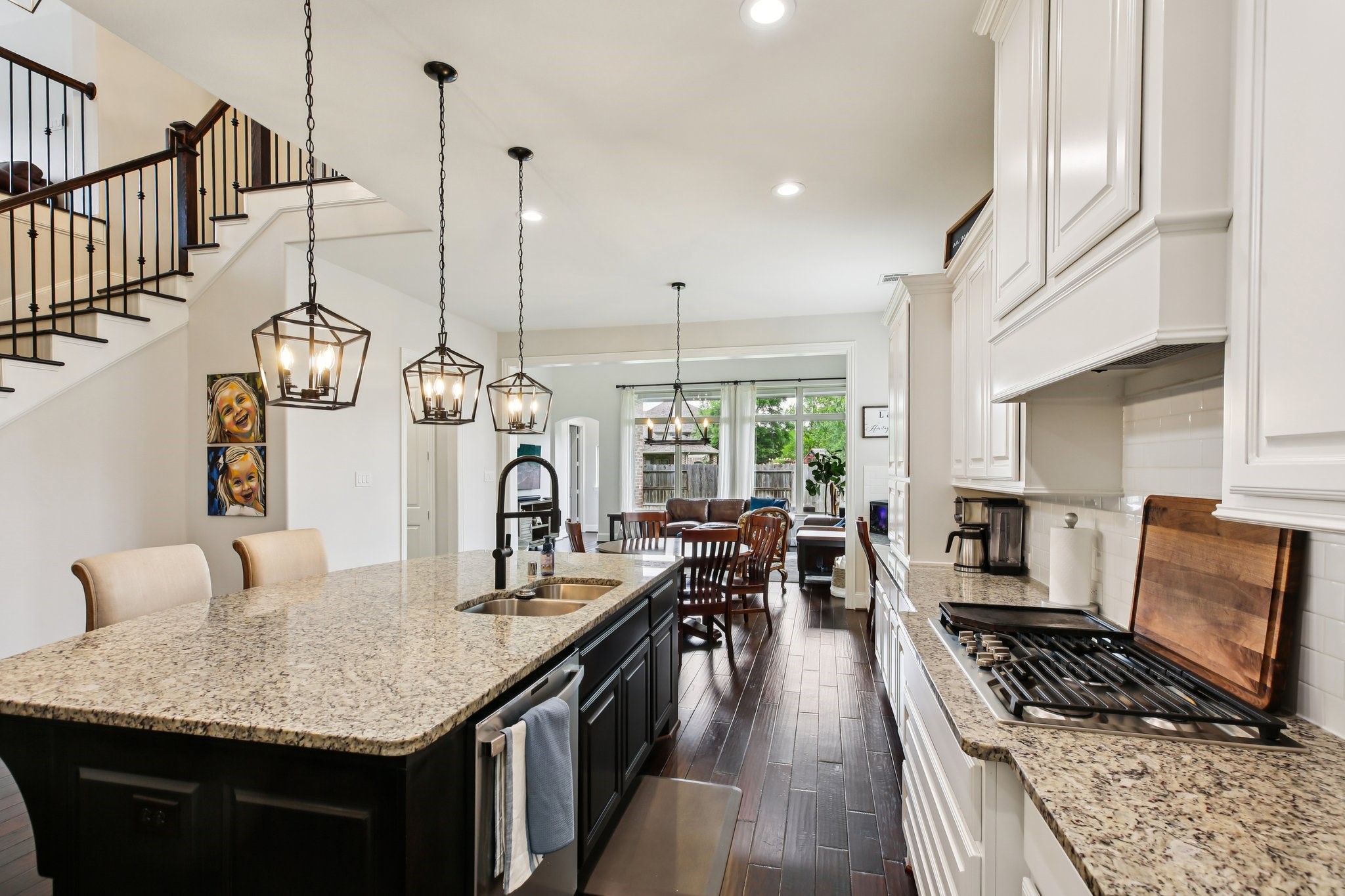 27914 Arden Trail Spring, TX 77386 - Photo 16 of 49 Spacious chef’s kitchen with an oversized granite island, breakfast bar seating, and stylish pendant lighting. Features include abundant white cabinetry, gas cooktop, and sleek tile backsplash, all complemented by rich wood flooring.