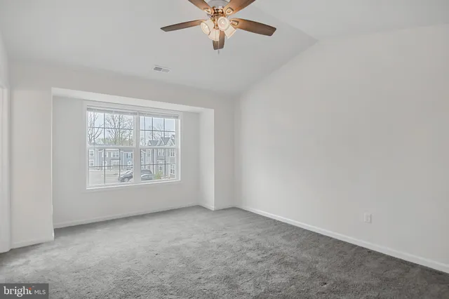 an empty room with a window and a fan