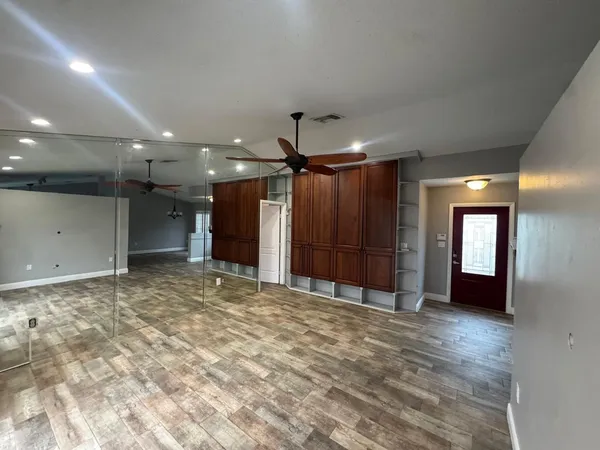 a view of an empty room with window and chandelier fan