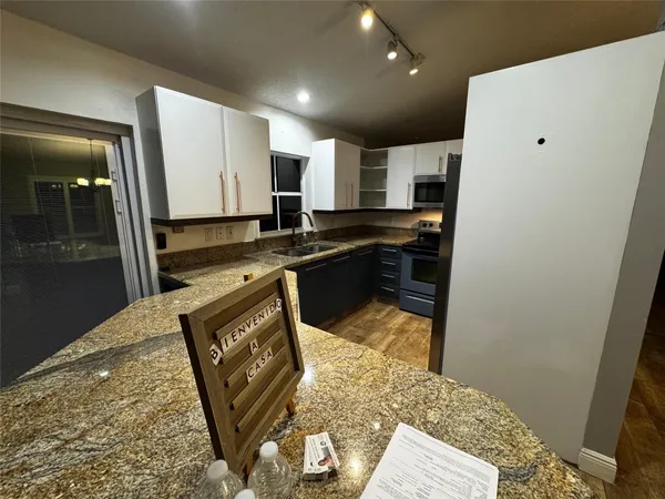 a kitchen with stainless steel appliances granite countertop a refrigerator a stove top oven and a sink