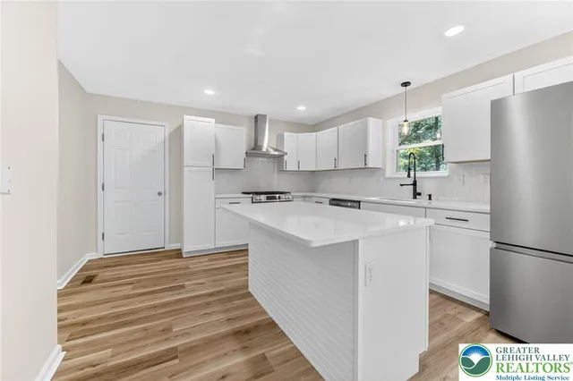 a kitchen with stainless steel appliances a refrigerator sink and white cabinets
