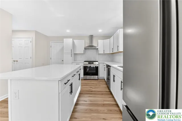a large kitchen with a white stove top oven and white cabinets