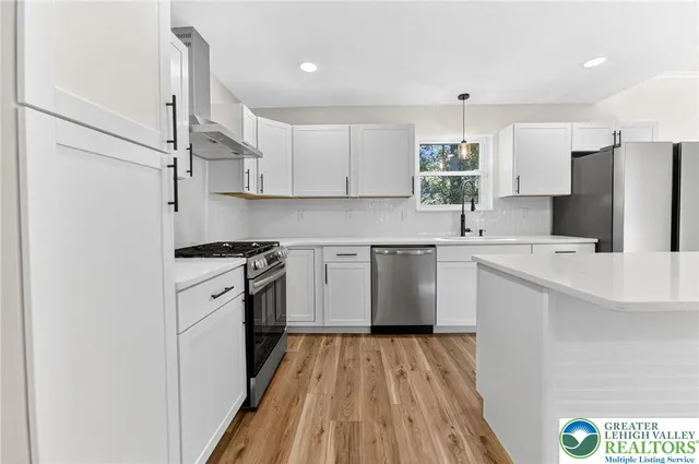 a kitchen with a sink a refrigerator and white cabinets