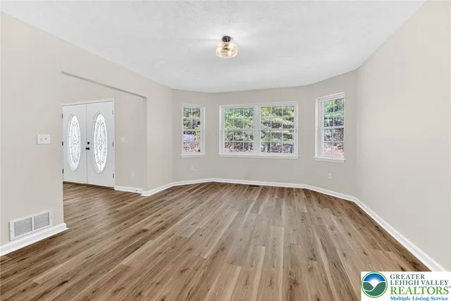 an empty room with wooden floor and windows
