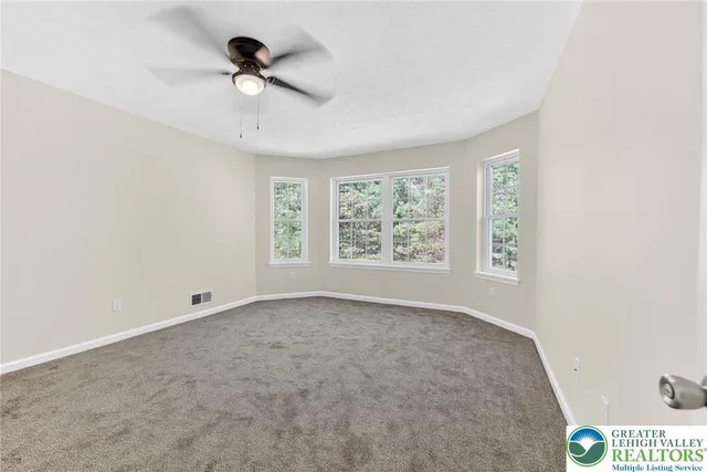 an empty room with windows and ceiling fan