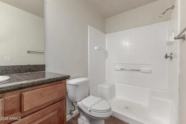 a bathroom with a granite countertop toilet a sink and shower